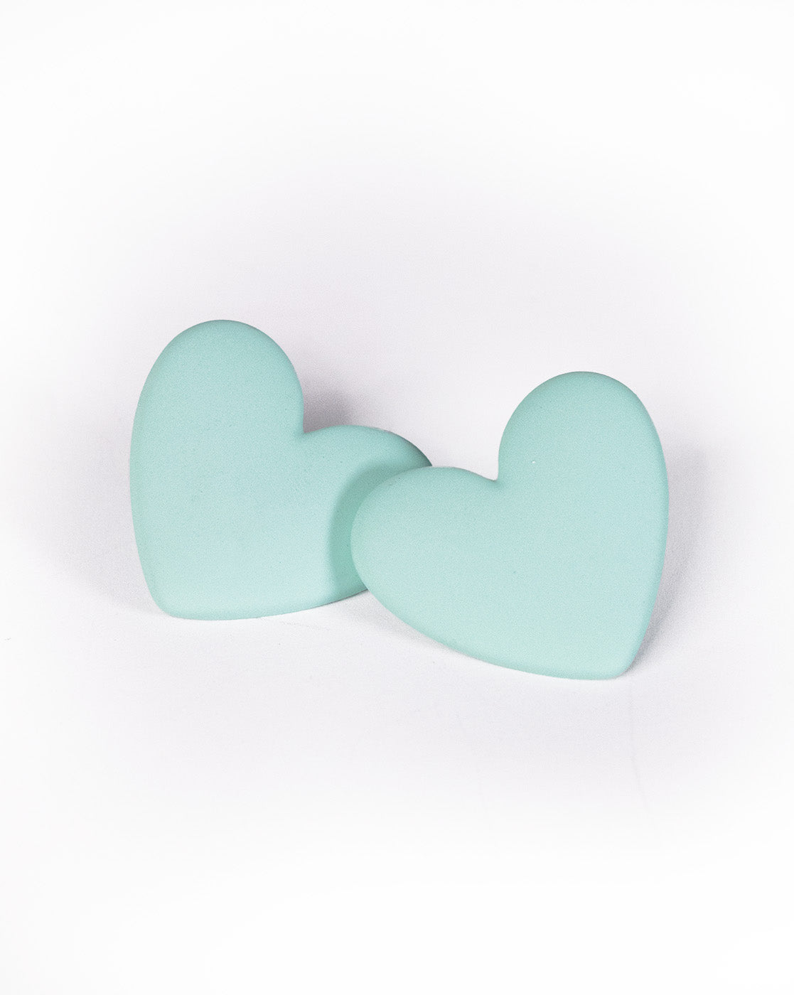 Two light blue, heart-shaped Love Hearts Earrings are placed next to each other on a white background.