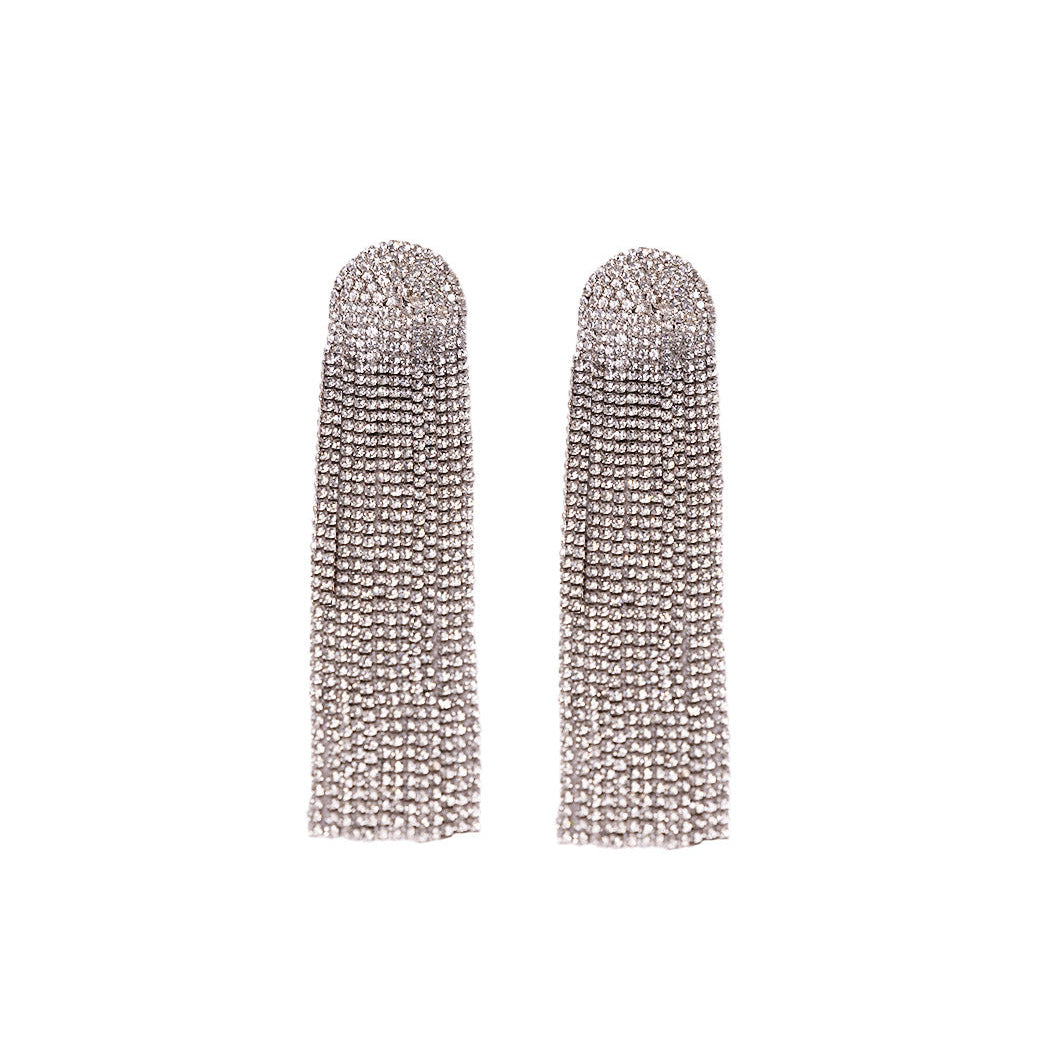The Zircon Shimmer Tassel Earrings feature long, silver-toned rhinestone tassels crafted from brass alloy with multiple dangling strands, displayed flat on a white background.