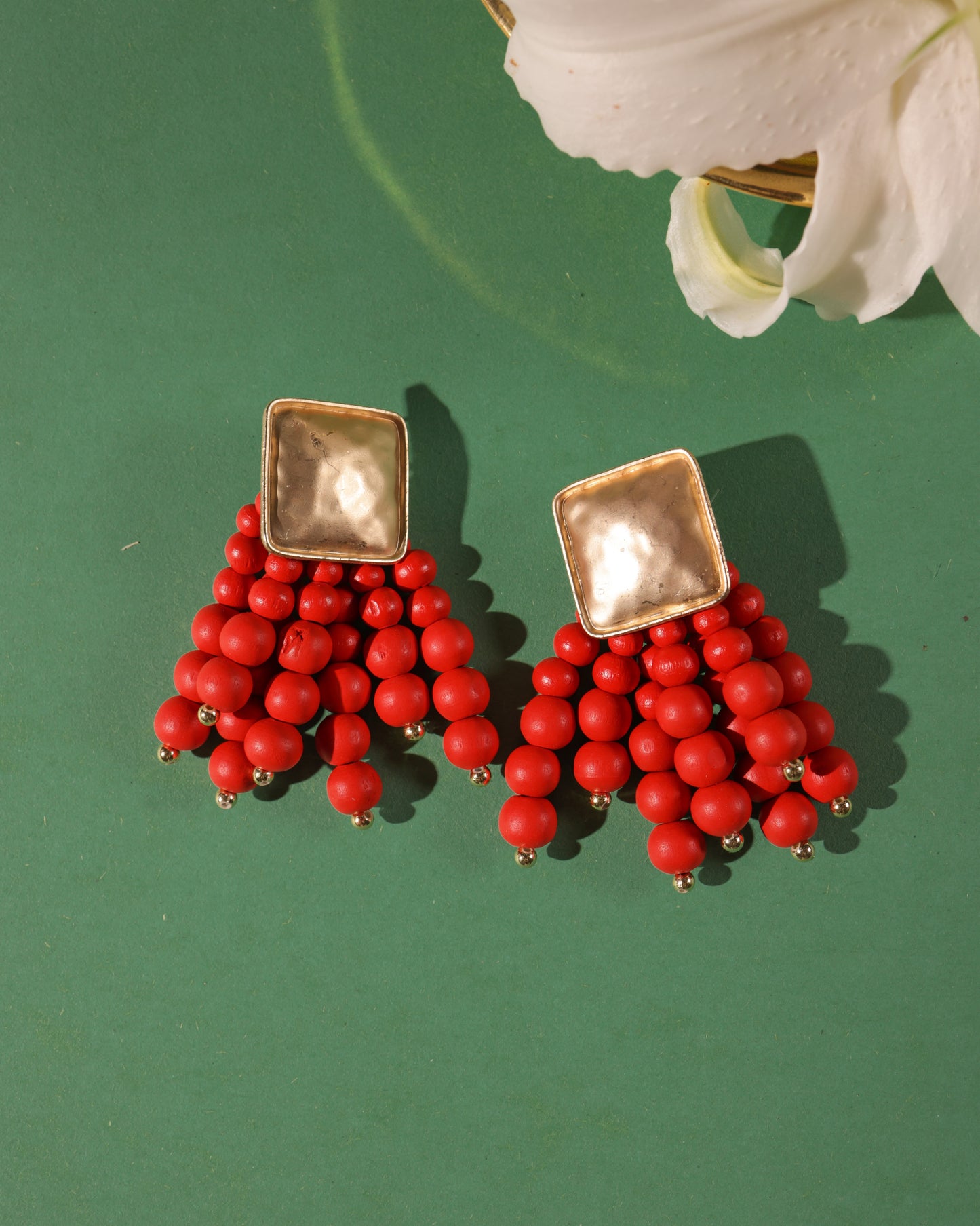 Beady Red and Gold Earrings: gold plated with square tops, multiple strands of round red beads. Displayed on green background with a white flower—perfect statement earrings for summer.