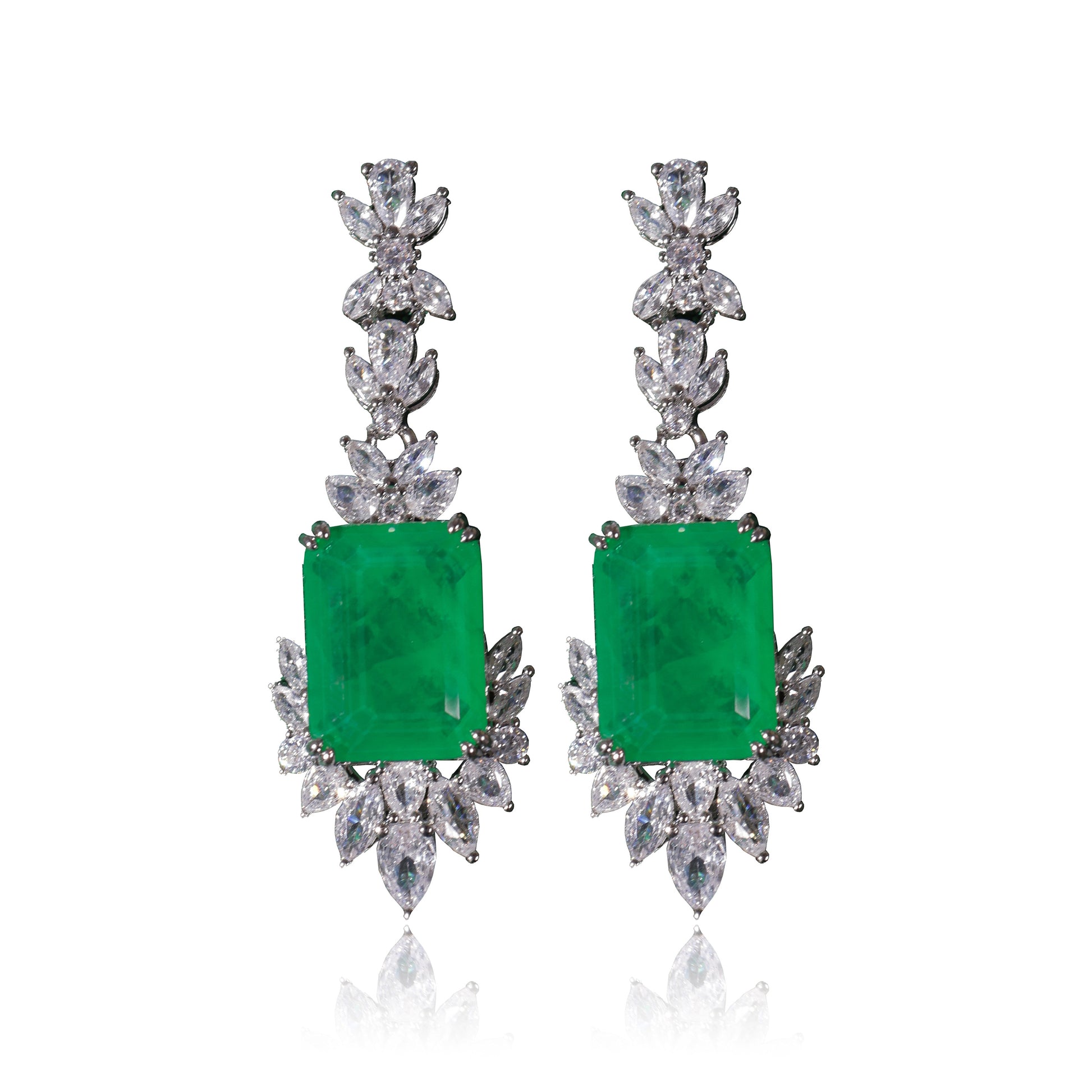 The Queen’s Earrings Set features elegant drop earrings with large rectangular green gemstones, accented by marquise-cut and round white stones, all set in silver metal.