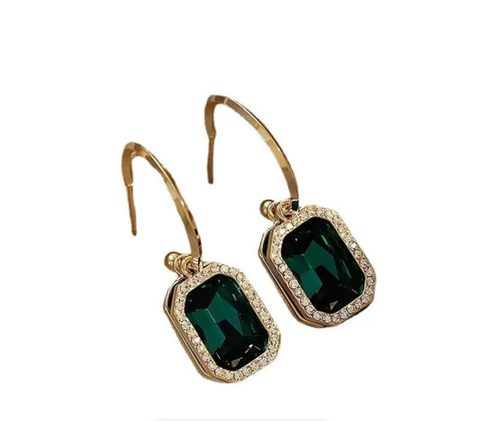 Green two layer earrings showcasing large emerald-cut green stones bordered by small clear stones, set against a white background for an elegant, classy look.