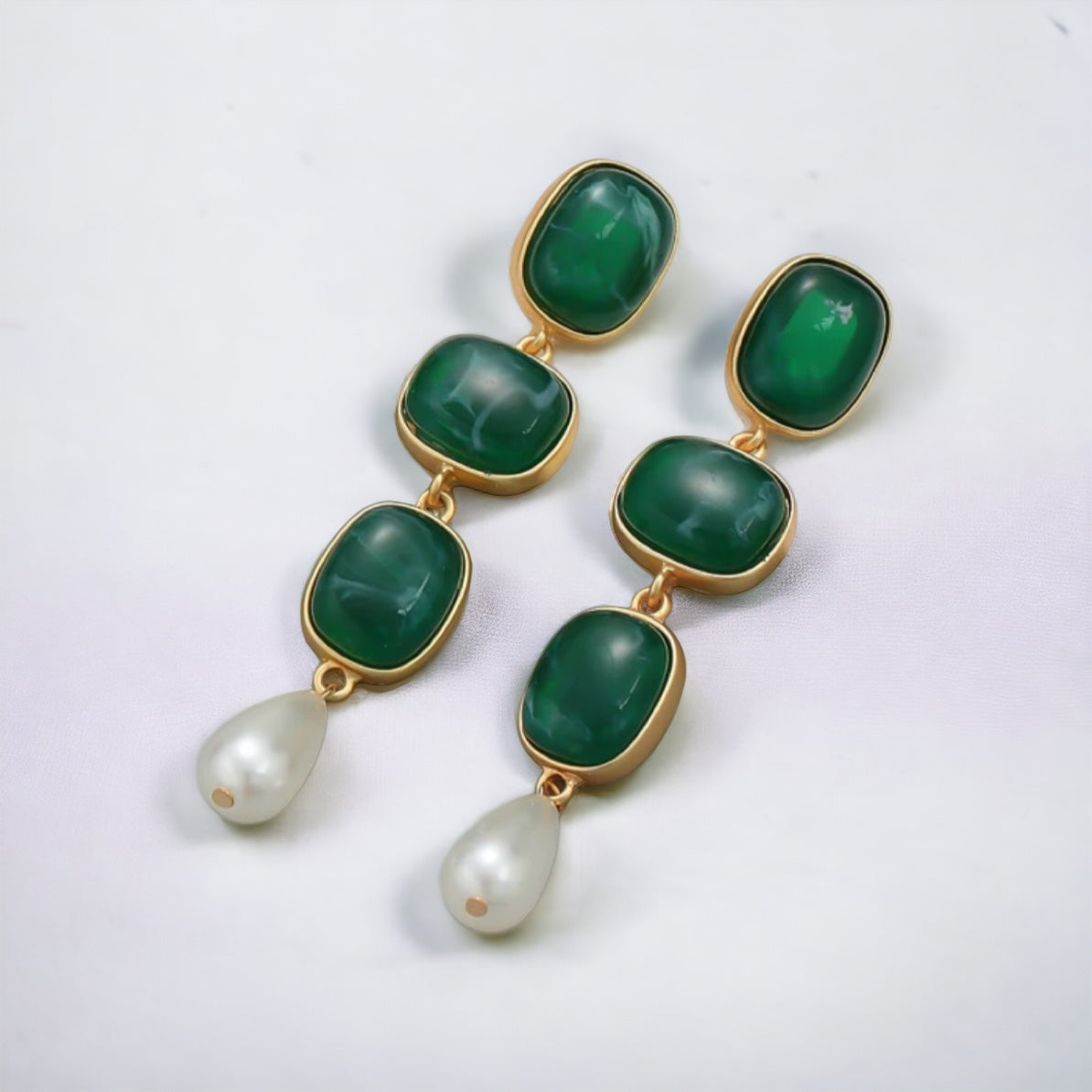 Green Enamel Danglers: 24K gold plated earrings featuring three rectangular green enamel stones and a teardrop-shaped white pearl drop on each, displayed on a white surface.