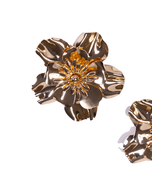 A pair of shiny, 24K gold plated flower earrings with detailed petals and a textured center are displayed on a white background. A smaller portion of matching earrings appears in the lower right corner. Product: Big gold flower earrings.