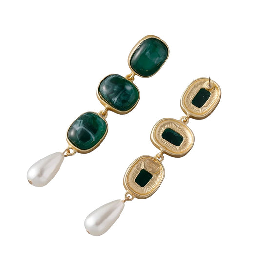The Green Enamel Danglers are 24K gold plated earrings with three rectangular green enamel stones and a teardrop-shaped white pearl at the end. One earring is shown from the front, the other from the back.